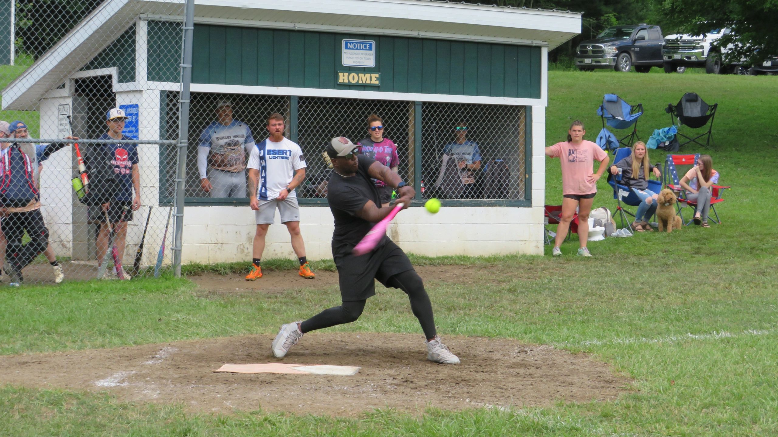 Man swinging a bat at a softball game with spectators watching.