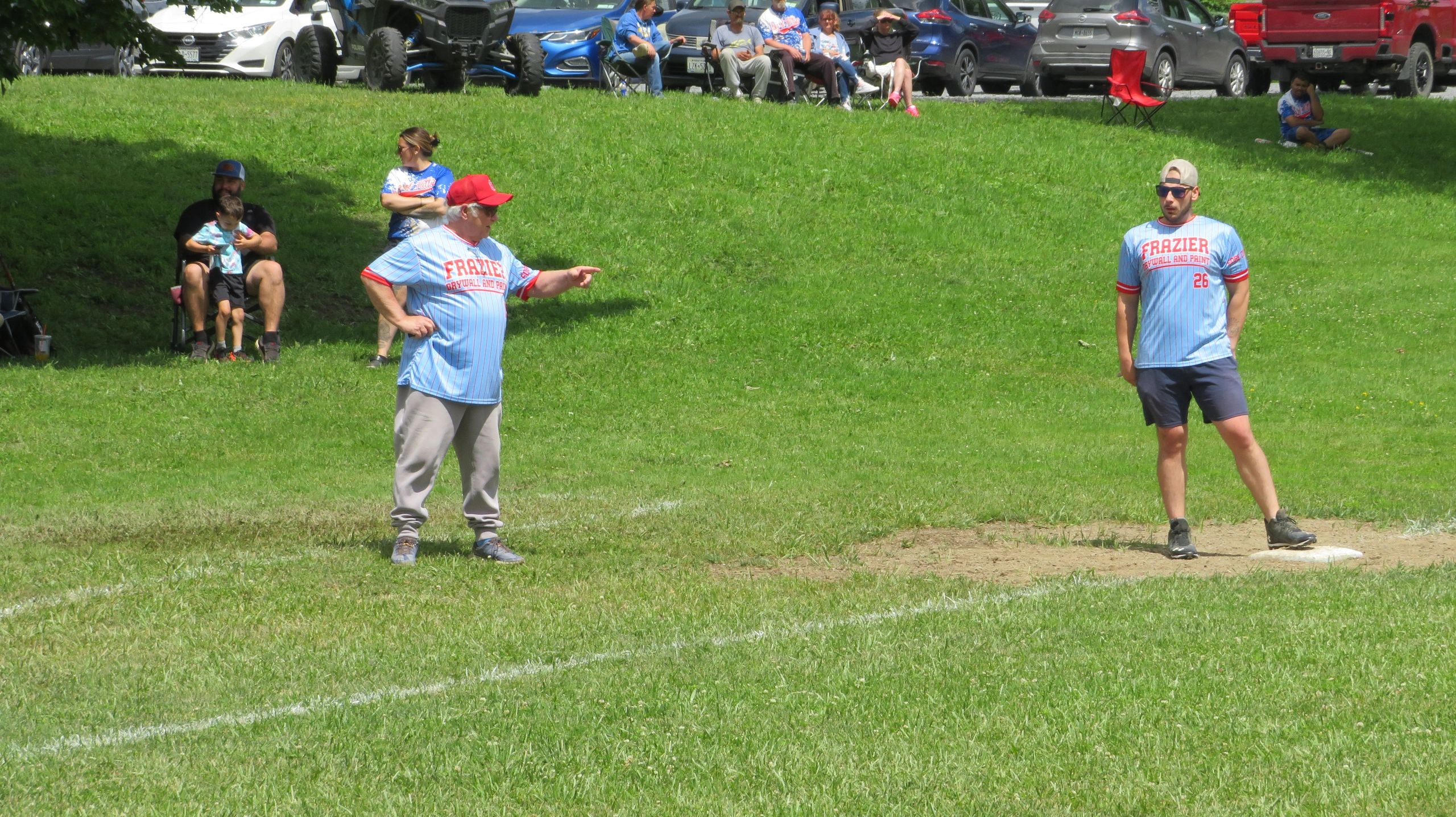 Two men in matching Frazier baseball uniforms on a grassy field.
