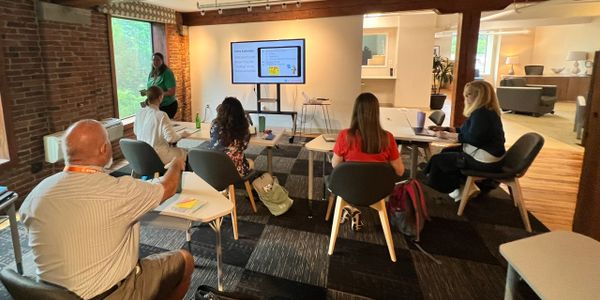 Adults attending a workshop or presentation in a brick-walled room.