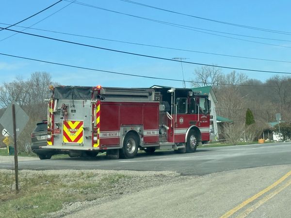 Red fire truck parked on a rural road under clear blue sky.