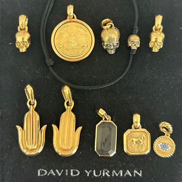 Collection of gold and gemstone David Yurman pendants on black background.