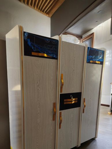 A white 3-door cupboard, 6ft x 5ft, with black contrast and golden lines, enhances beauty.