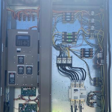 Electrical control panel with wiring and circuit breakers organized inside.