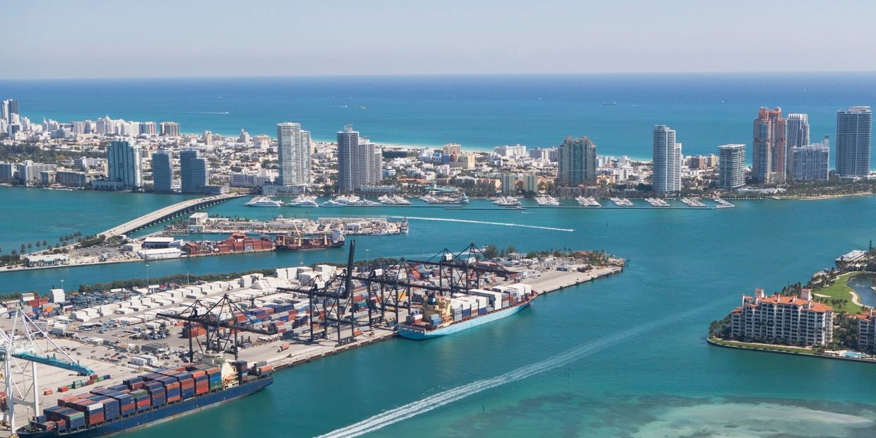 Aerial view of a coastal city with shipping docks and skyscrapers.