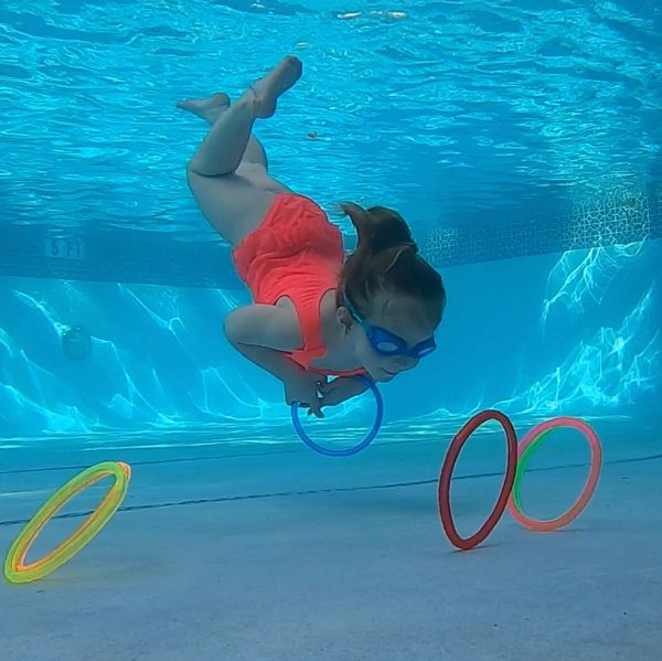 A girl swimming in the pool with hoops.