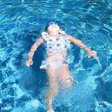 A baby girl relaxing in the swimming pool.