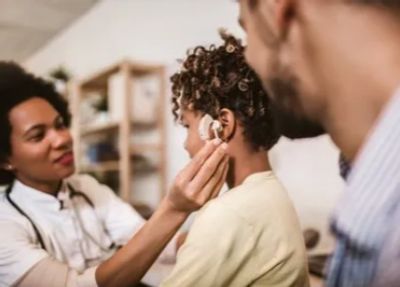 Audiologist with pediatric patient and parent fitting hearing aid