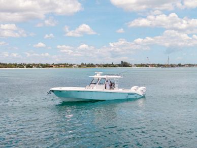 A white motorboat on calm blue water with a distant shoreline.