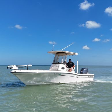 White motorboat on calm water under blue sky.