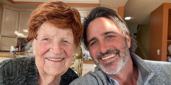 Smiling elderly woman and middle-aged man taking a close selfie indoors.