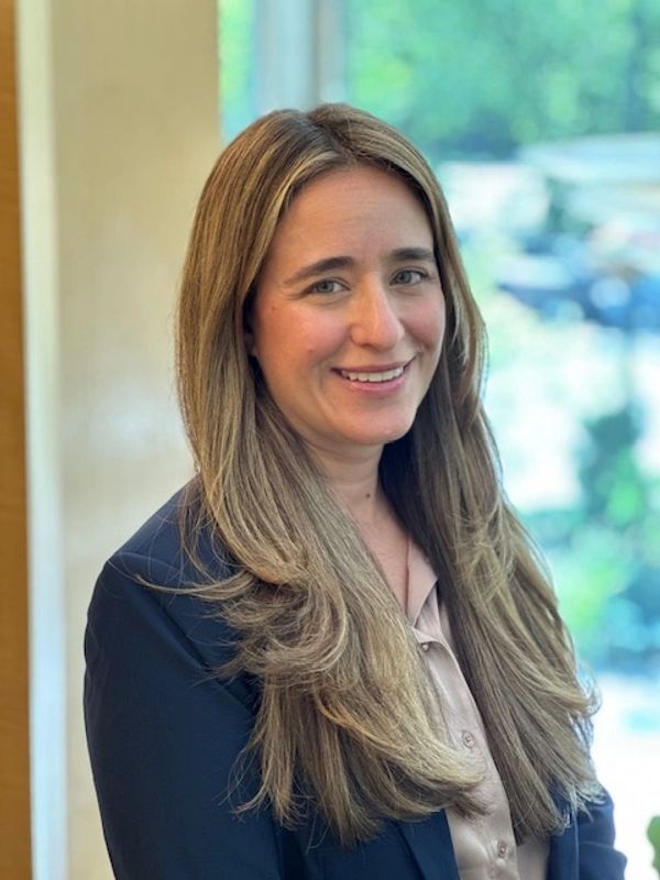 Smiling woman with long light brown hair in business attire.