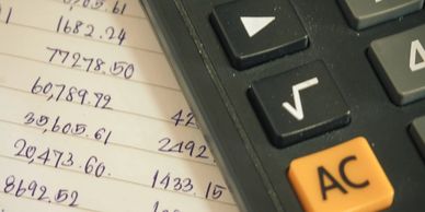 A black calculator on a piece of paper with random numbers written on it.