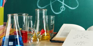 A chemistry set consisting of beakers next to two open books.
