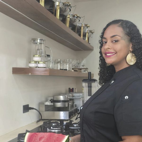 Mujer sonriente con uniforme negro en cocina moderna.