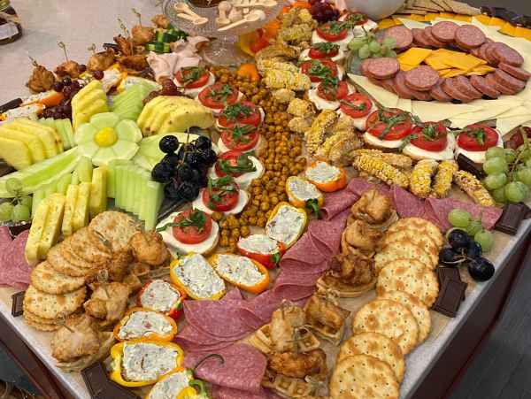 Mesa con variedad de frutas, quesos, embutidos y aperitivos.