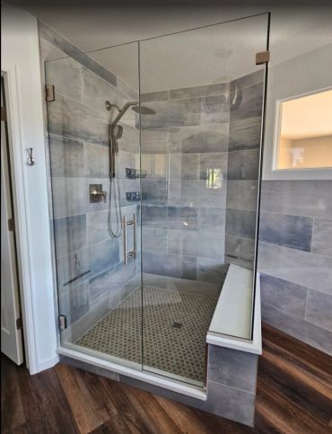 Modern glass shower enclosure with tiled walls and built-in bench.