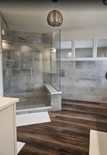 Modern bathroom with glass shower and wood-style flooring.
