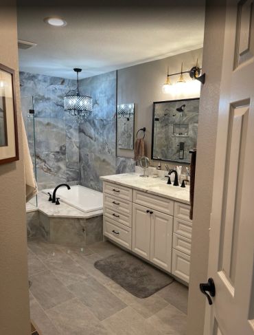 Elegant bathroom with marble bathtub surround and chandelier lighting.