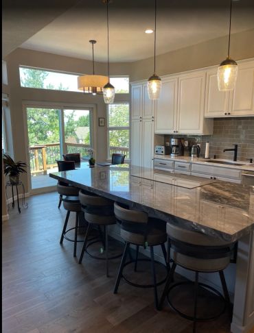 Modern kitchen with marble island and pendant lights overlooking a deck.