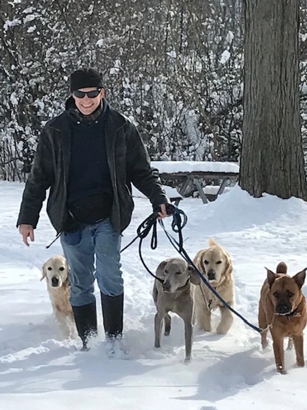 Smiling man, David, walking four dogs in the snow