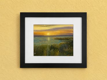 Framed painting of a sunset over a marshland with grasses and water.