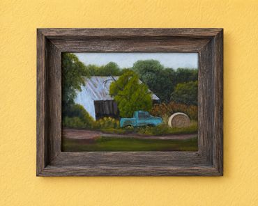 Rustic painting of an old barn and blue truck in a wooden frame.