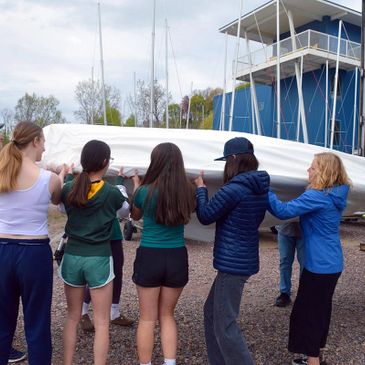 Group of people carrying a boat near a marina.