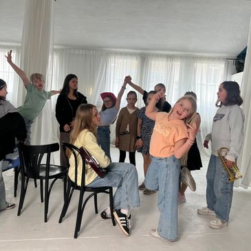 Group of children having fun indoors, some playing instruments.