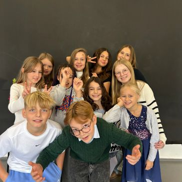 A group of happy children posing together in front of a dark backdrop.