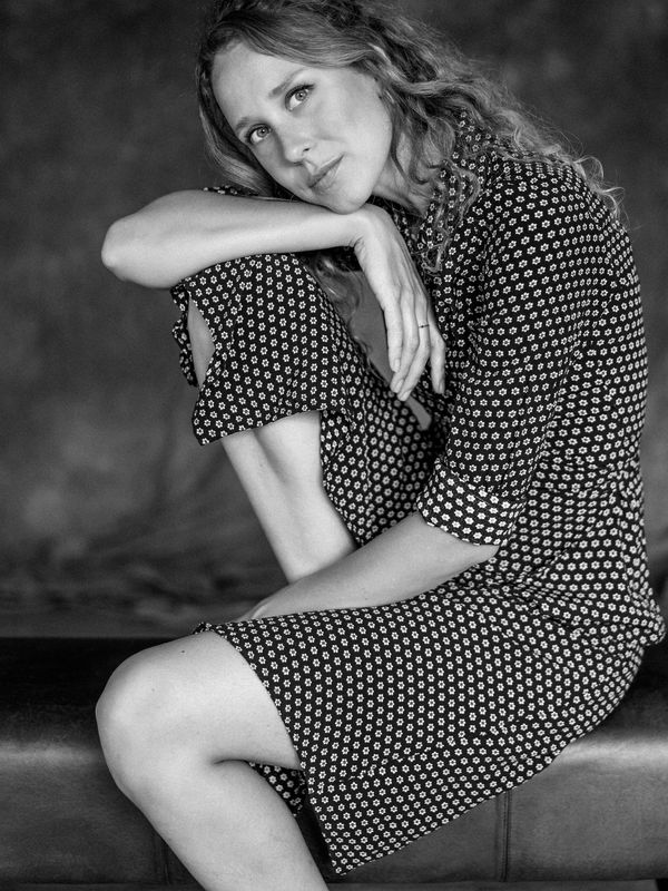 Black and white portrait of a woman sitting thoughtfully with a floral dress.