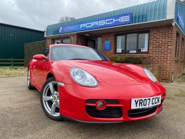 Red Porsche sports car parked outside a dealership.