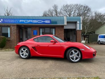 Red Porsche sports car parked outside Wight Porsche building.