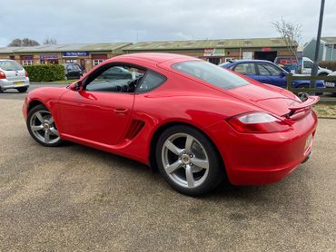 Red Porsche sports car parked in an outdoor lot.