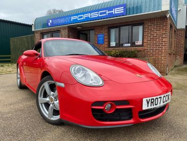 Red Porsche sports car parked outside Wright Porsche dealership.