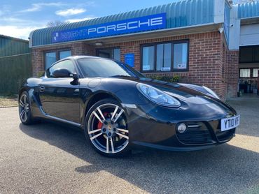Black Porsche sports car parked outside a Porsche dealership.