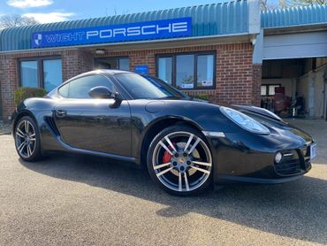 Black Porsche sports car parked outside Wight Porsche dealership.