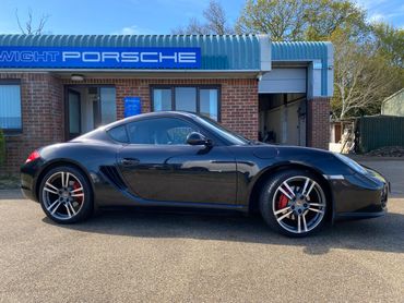 Black Porsche sports car parked outside a dealership.