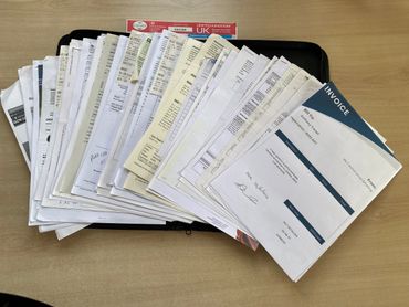 A large stack of assorted documents and invoices on a table.