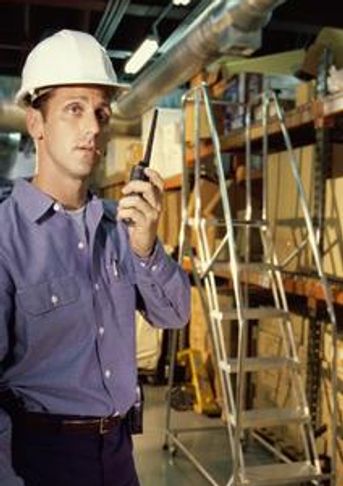 Man in hardhat using radio.
