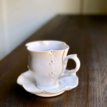 Elegant white porcelain cup and saucer on a wooden surface.