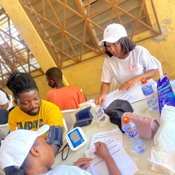 Community health workers checking blood pressure and filling health forms.