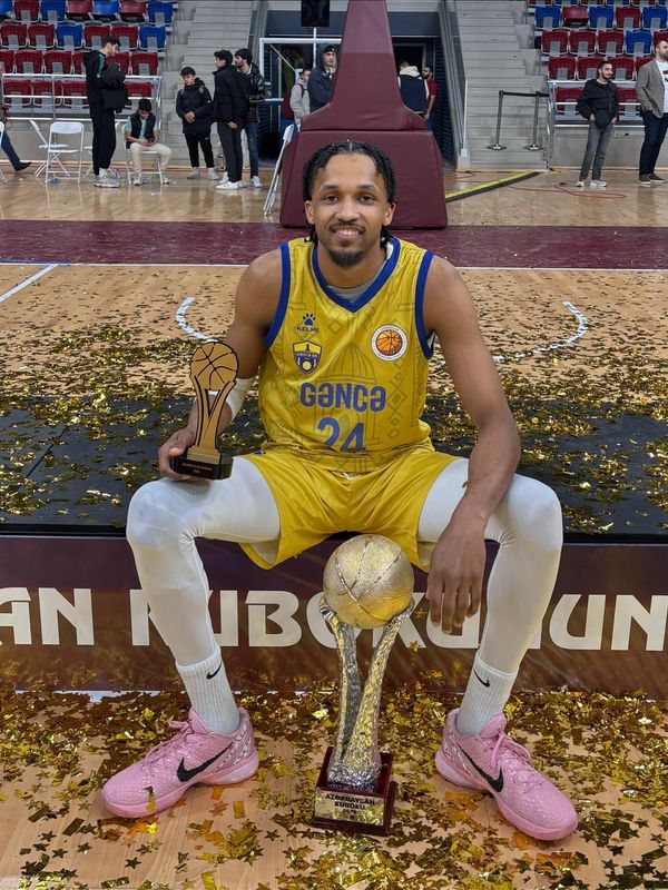 Basketball player with trophies and confetti on court.