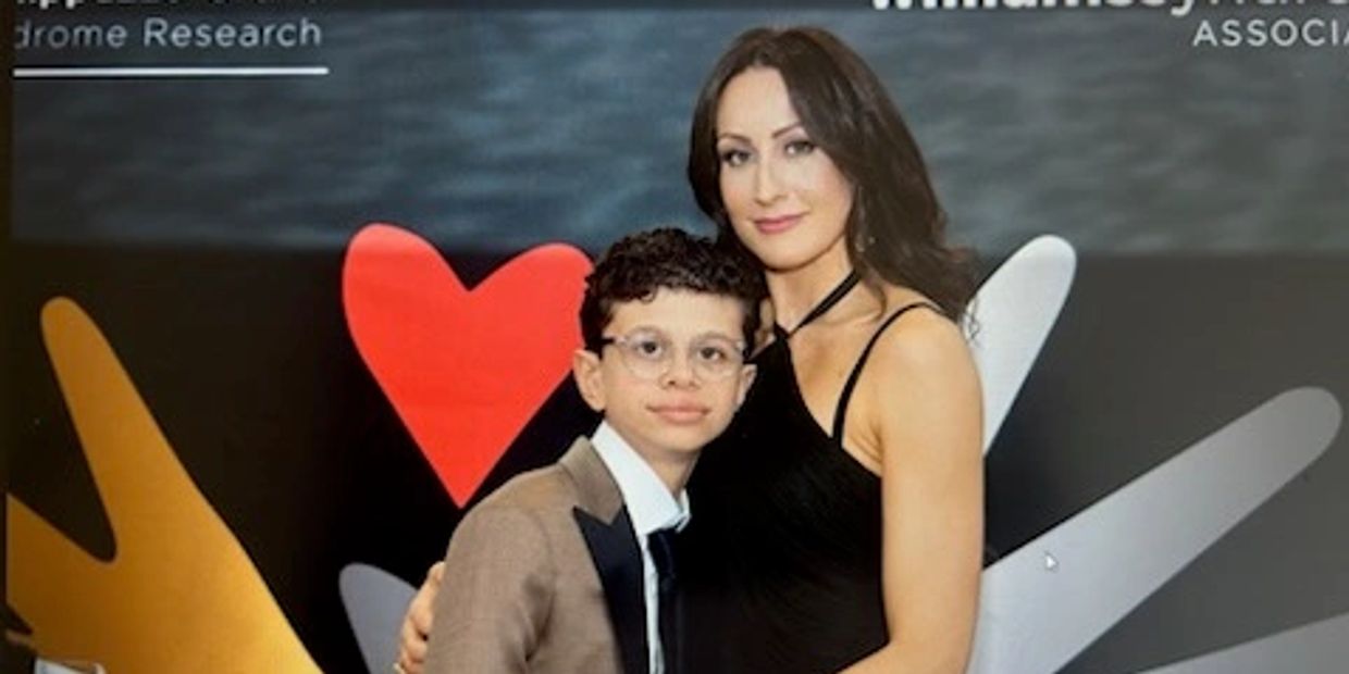 Woman and boy dressed formally in front of colorful backdrop with heart.