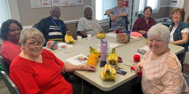 Group of seniors crafting with yarn and bananas.