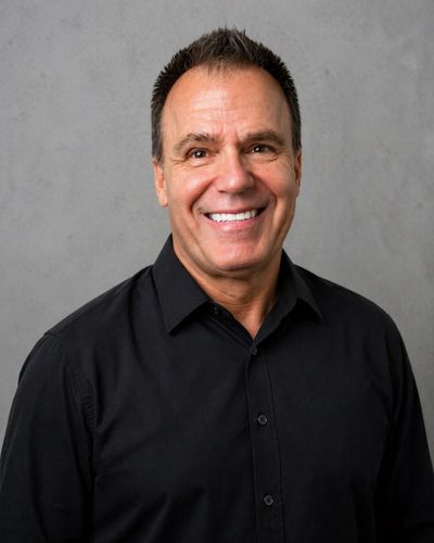 Smiling man in a black shirt against a gray background.