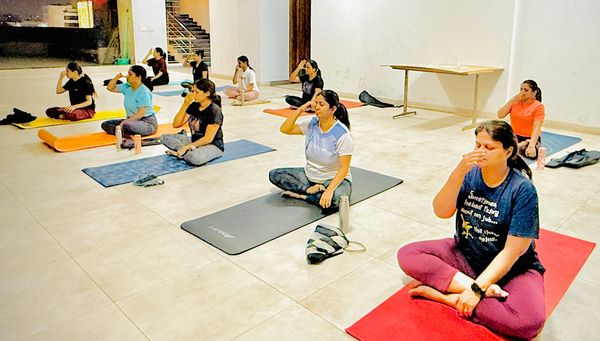 Group yoga class practicing meditation and breathing exercises on colorful yoga mats in Bangalore