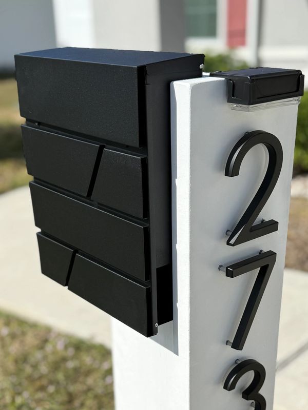 Modern black mailbox with house number 2734 on a white post.