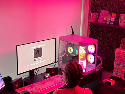 Person gaming at a PC with ambient pink lighting.