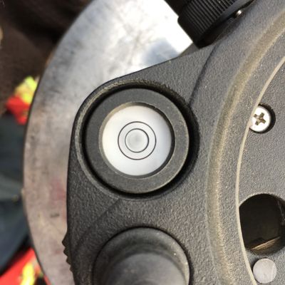 Close-up of a circular bubble level on a device with adjustment knobs.
