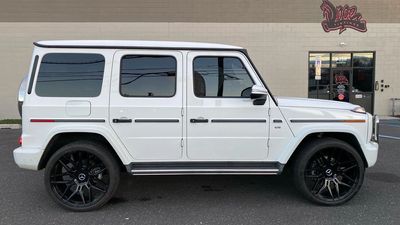White luxury SUV with black rims parked outside a building.